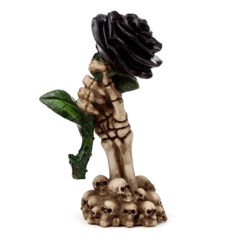La main squelette tient un accessoire de maison rose noire